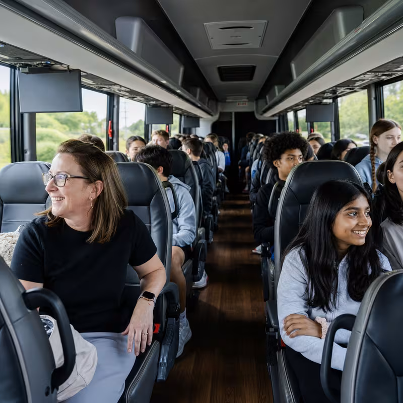 Group boarding a white charter bus for School Transportation transportation in Encinitas